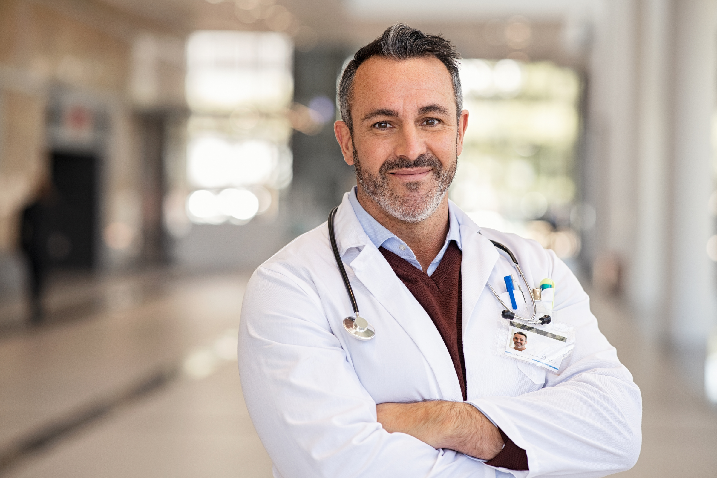 Mediziner im weißen Kittel steht auf einem Klinikflur.