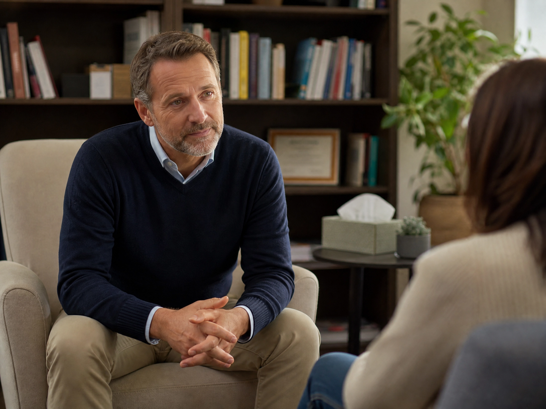 Ein freundlicher Mann mit positiver Ausstrahlung, der einer Patientin zuhört. Er ist Diplom-Psychologe.
